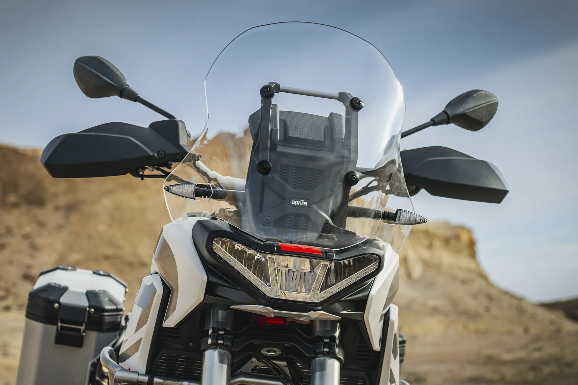 Aprilia Tuareg 660 vue de face dans un décor désertique, projecteurs allumés